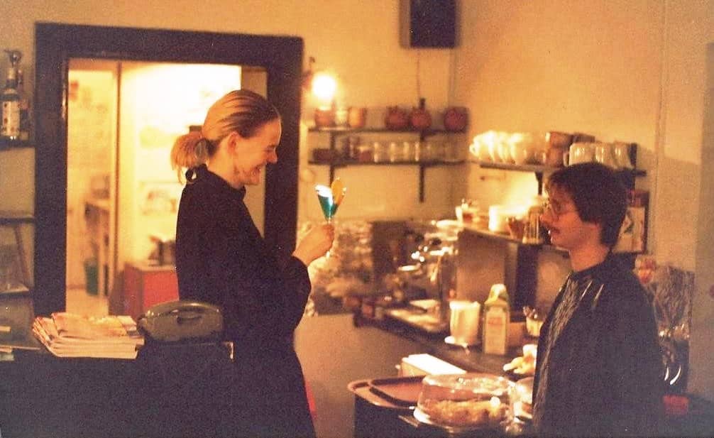 Unternehmerin sein - Ulla mit Cocktail und Gast im Café Cralle, ca. 1990, im Hintergrund Geschirr, Kaffeemaschine