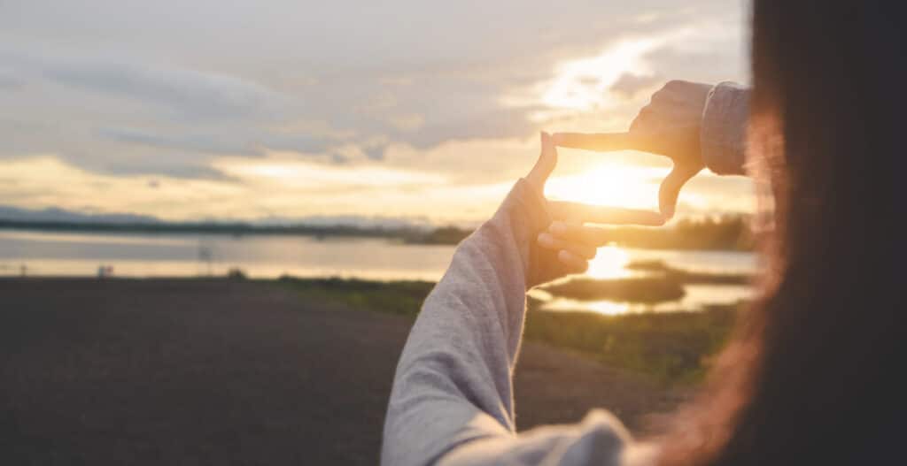 Close up von Frau Hände machen Rahmen Geste mit Sonnenuntergang am Himmel, Weibliche Erfassung der Sonnenaufgang, Sonnenlicht im Freien, Zukunftsplanung,