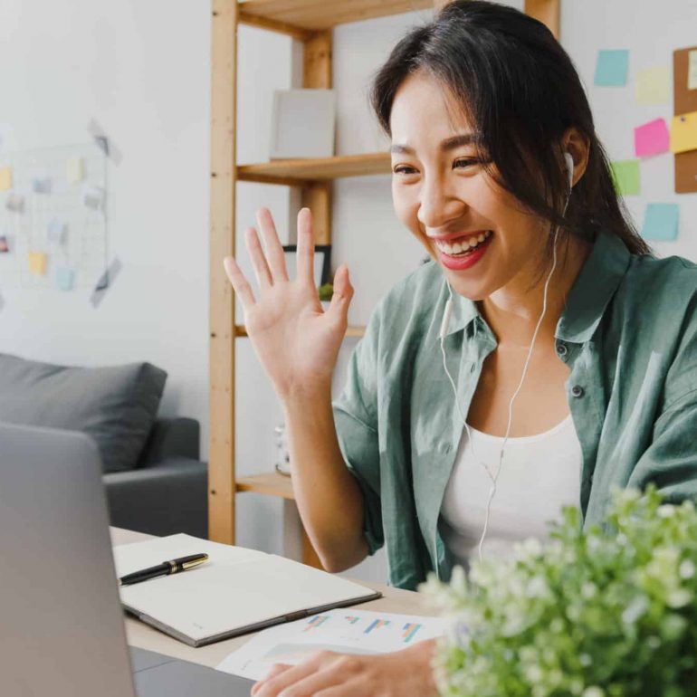 Asia businesswoman using laptop talk to colleagues about plan in video call while smart working from home at living room. Self-isolation, social distancing, quarantine for corona virus prevention.
