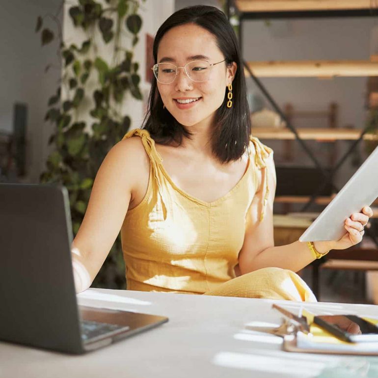 Thinking, research and tablet with asian woman and laptop in startup for management, planning or goals. Idea, vision and creative with small business owner for branding, agenda or web design.